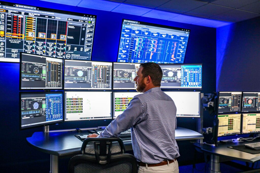Man in remote operations standing in front of many monitors